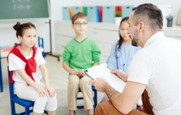 School Psychologist Reading Document While Siting In Front Of Elementary School Psychologist Reading Document While Siting In Front Of Elementary