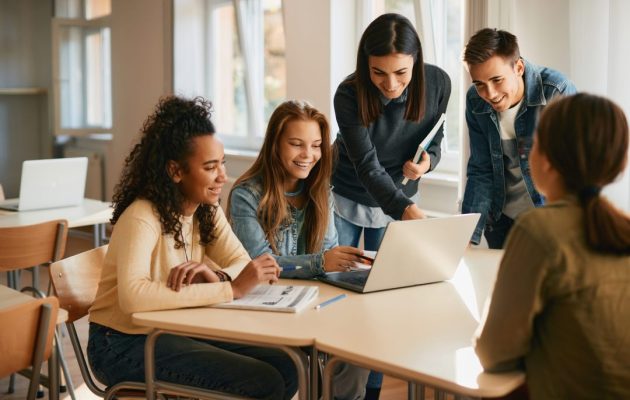Happy,High,School,Teacher,Assisting,Her,Students,With,E-learning,During Happy,High,School,Teacher,Assisting,Her,Students,With,E-learning,During