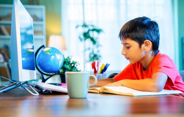 Indian Asian Small Boy Sitting At Desk In Modern Home Indian Asian Small Boy Sitting At Desk In Modern Home